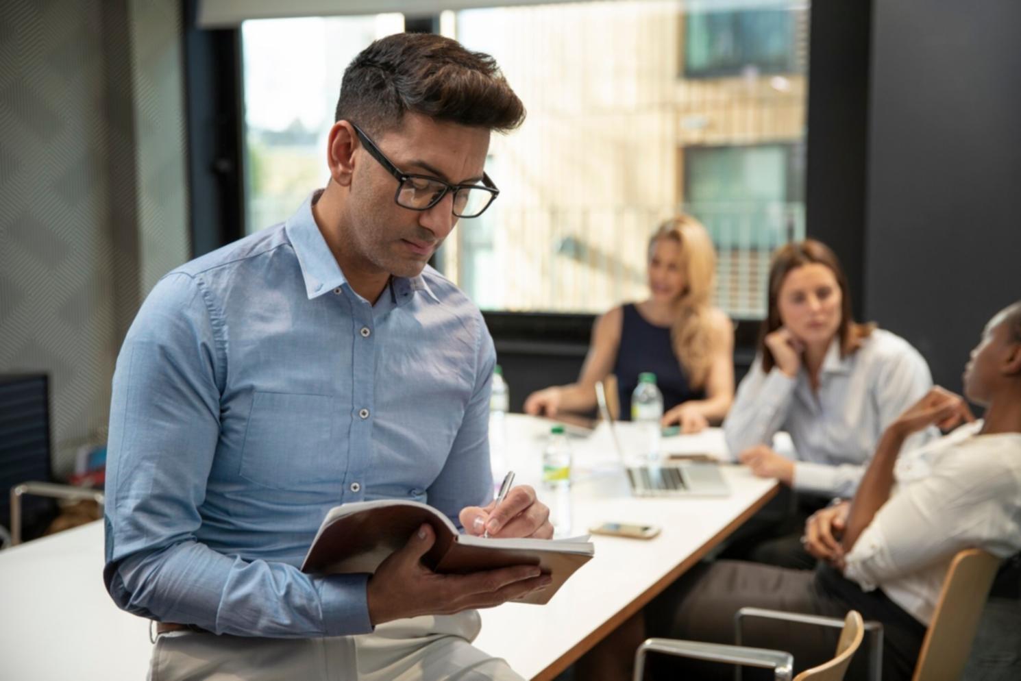 Person reviewing budget documents with calculator and laptop